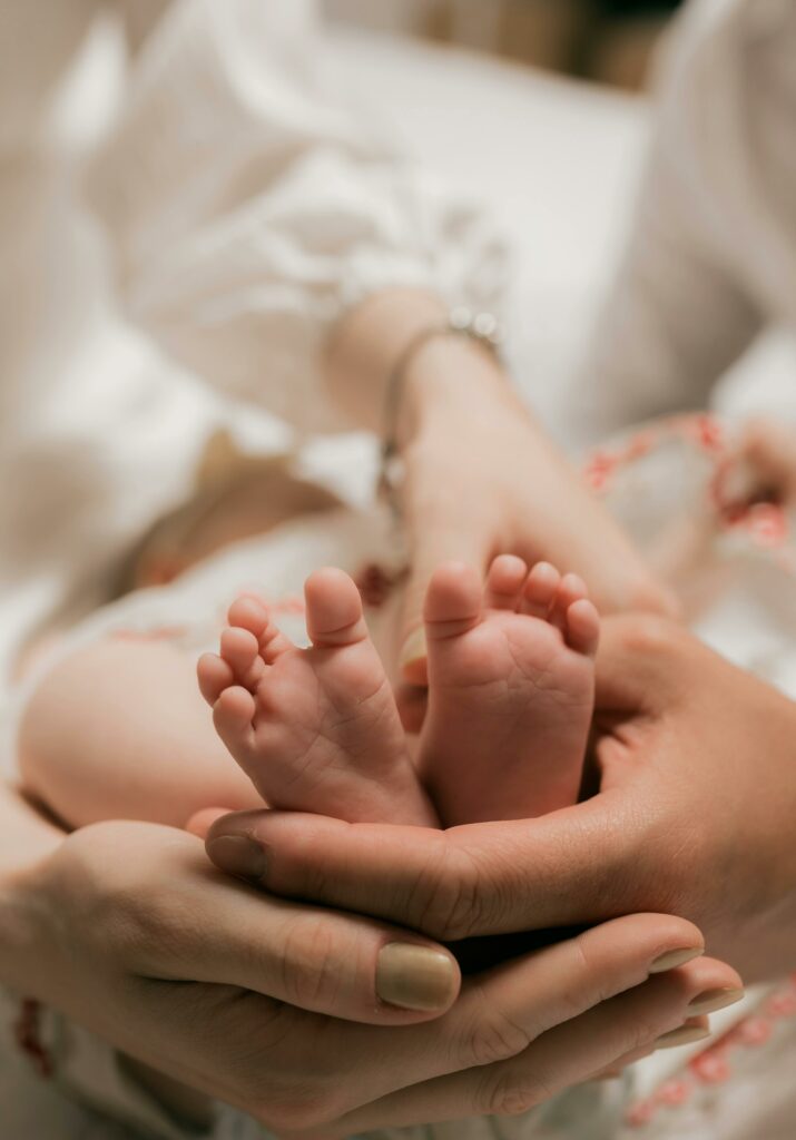 pexels photo 35119982 35119982 A close-up of a baby's tiny feet cradled gently by loving parents' hands in a warm setting.